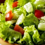 A visually appealing green salad with crisp lettuce, cucumbers, and red onions dressed in vinaigrette.