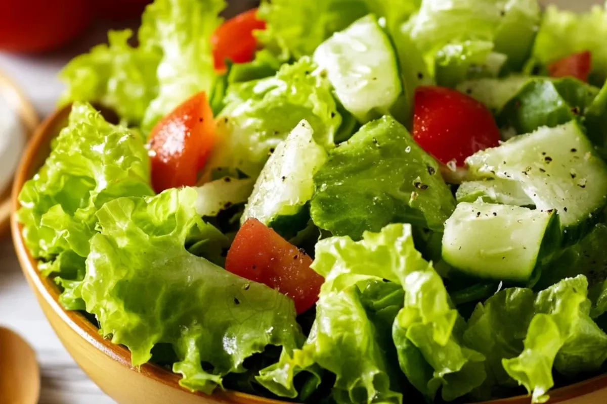 A visually appealing green salad with crisp lettuce, cucumbers, and red onions dressed in vinaigrette.