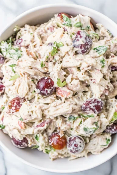 A close-up of Chicken Salad with Grapes and Pecans in a white bowl