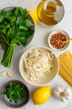 Ingredients for leftover rotisserie chicken pasta no cream on a white marble surface.
