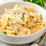 Bowl of Cozy Leftover Rotisserie Chicken Pasta topped with Parmesan and parsley.