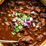 Spoonful of steak chili with beans and toppings.